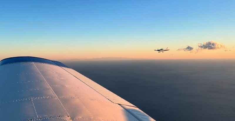 Das Flugzeug im Flug bei Sonnenuntergang, mit dem goldenen Hintergrund des Himmels über dem Flughafen von Villanova d'Albenga