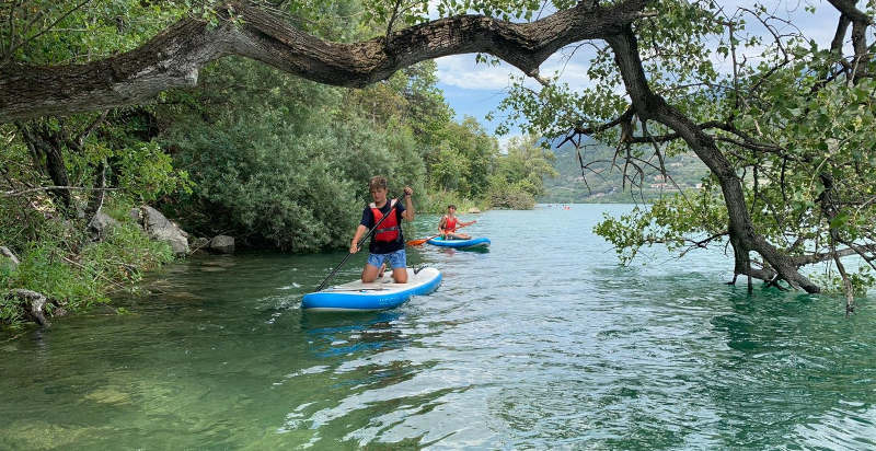 Personen auf einem SUP-Board in der Baia del Corno am Gardasee