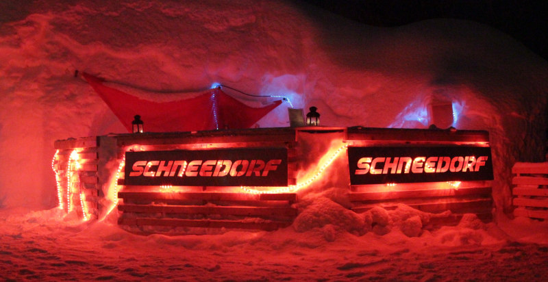 Outdoor-Schneebar im Schneedorf mit Blick auf die verschneiten Berge