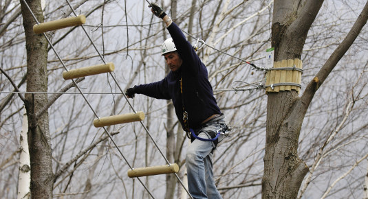 Teilnehmer auf einem Hochseil-Parcours im Abenteuerpark Veglio