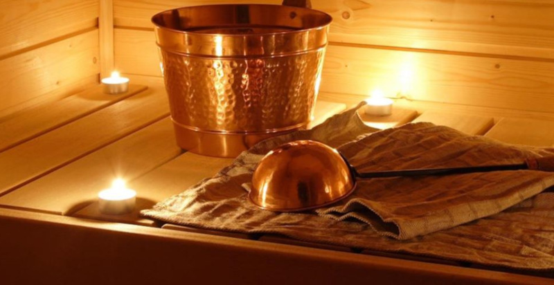 Detailaufnahme der Holzbank und Aufgusskübel in der finnischen Sauna